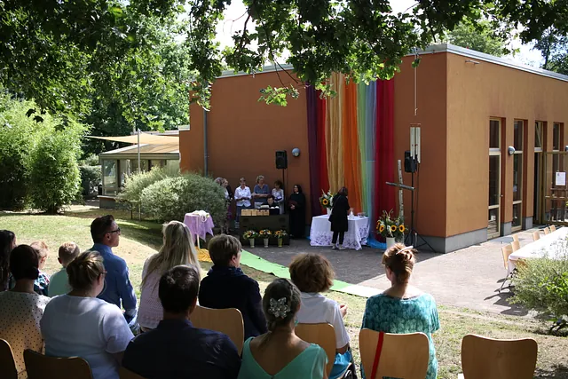 Rückansicht des Gemeindezentrums bei einem Gottesdienst mit Altar und Regenbogenfahne